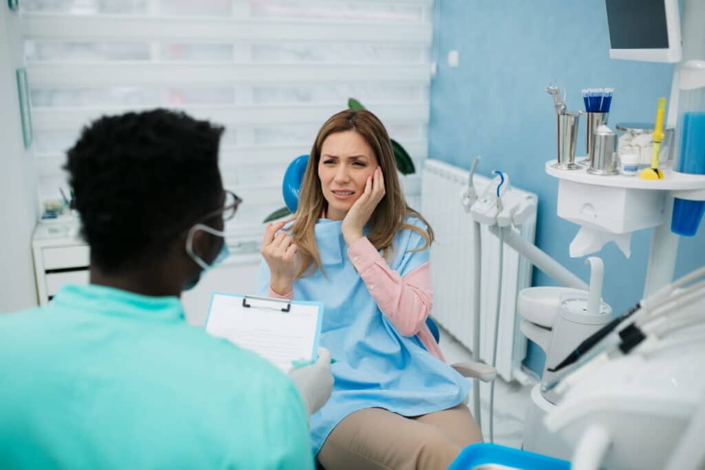 A dentist is about to help a woman in severe dental pain after experiencing a dental emergency. 