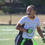 A kid playing a sport while wearing a blue mouthguard.