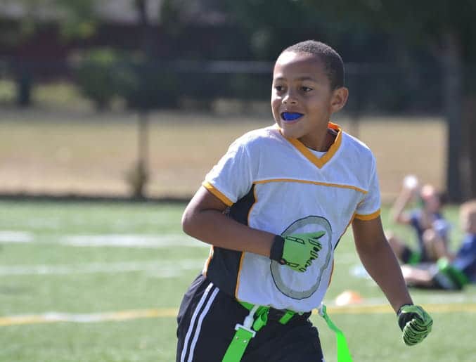 A kid playing a sport while wearing a blue mouthguard.