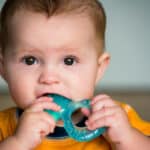 A teething baby chewing on a teether.