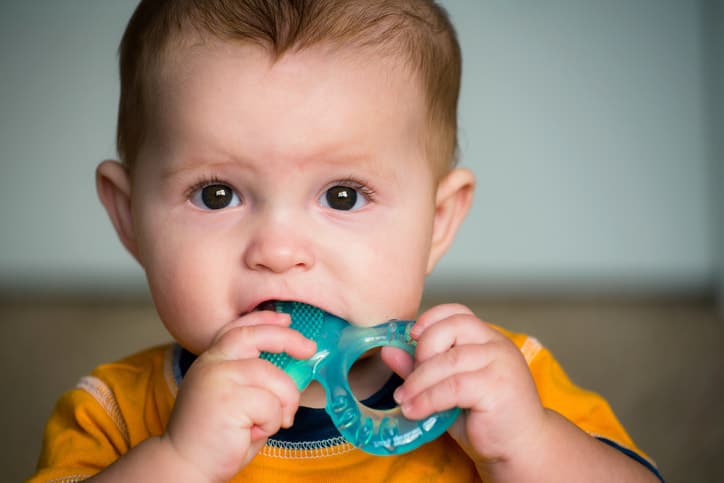 A teething baby chewing on a teether.