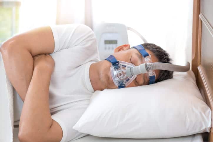 A man sleeping with a sleep apnea mask on.