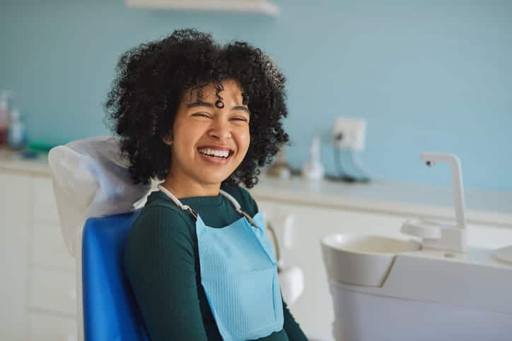 A girl smiling at the dentist's office after having her braces removed.