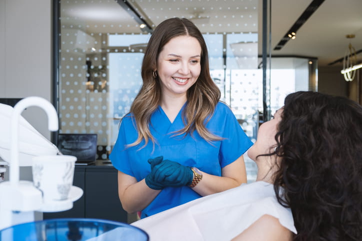 A dental hygienist smiling as she speaks with one of her patients