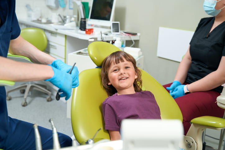 A young child smiling in a dental chair.